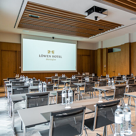 Moderner Konferenzsaal mit Stuhl-und Tischreihen und großer Leinwand im Löwen Seminarhotel 